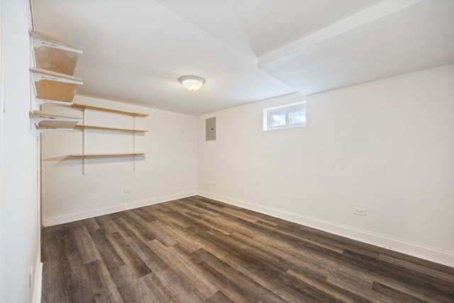 basement with dark wood-style floors, baseboards, and electric panel
