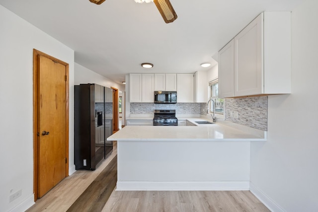 kitchen with black appliances, light countertops, decorative backsplash, a sink, and a peninsula