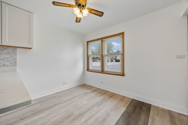 unfurnished dining area featuring light wood-style flooring, a ceiling fan, and baseboards