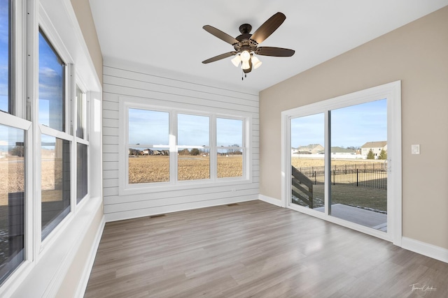 unfurnished sunroom featuring wood finished floors and baseboards