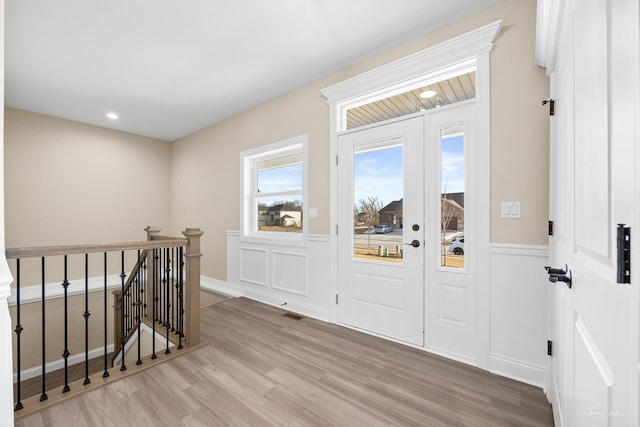 entrance foyer with light wood-style flooring, recessed lighting, and a wainscoted wall