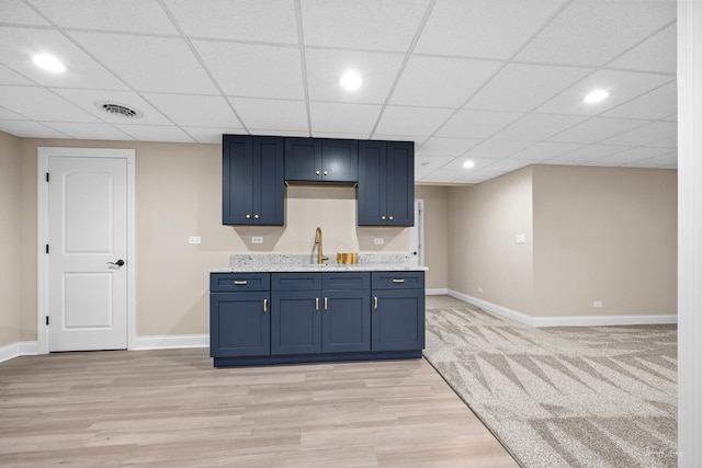 kitchen with baseboards, light wood-type flooring, blue cabinetry, a drop ceiling, and recessed lighting