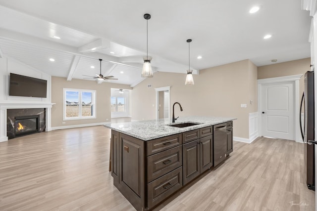 kitchen featuring a sink, appliances with stainless steel finishes, light wood-style floors, a fireplace, and dark brown cabinetry
