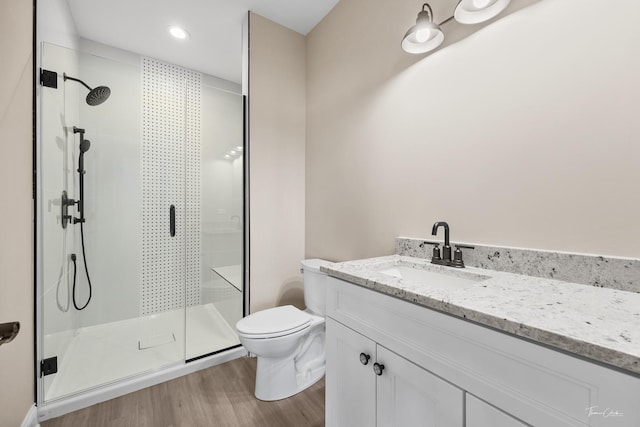 full bath featuring toilet, a stall shower, wood finished floors, and vanity
