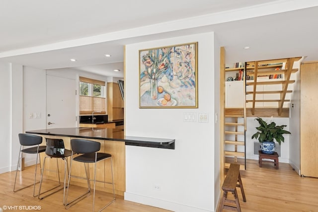 58 W Schiller St, Chicago, IL 60610 - kitchen with dark countertops, a kitchen bar, light wood-style floors, a peninsula, and recessed lighting