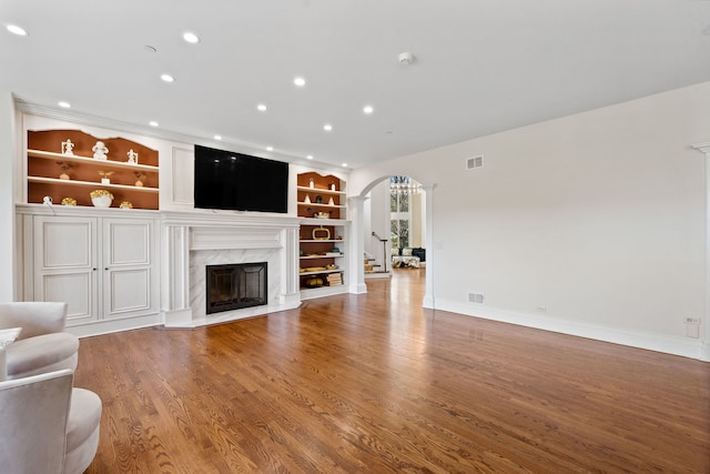 6590 Beech Ln, Libertyville, IL 60048 - unfurnished living room featuring arched walkways, a premium fireplace, recessed lighting, built in shelves, and ornate columns