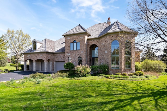 6590 Beech Ln, Libertyville, IL 60048 - french provincial home with brick siding, asphalt driveway, a front yard, a chimney, and a garage