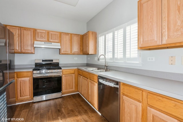 kitchen featuring appliances with stainless steel finishes, a sink, under cabinet range hood, dark wood-style flooring, and light countertops