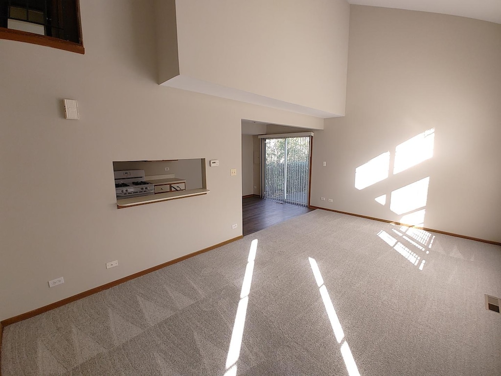 270 Butternut Ln, Streamwood, IL 60107 - unfurnished living room featuring carpet flooring, baseboards, and a towering ceiling