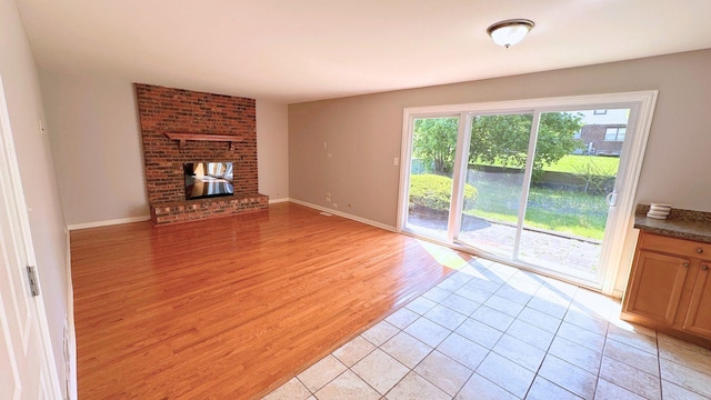 unfurnished living room with light wood-type flooring, a fireplace, and baseboards
