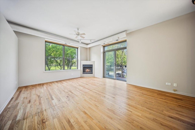 811 S Lytle St Unit 101, Chicago, IL 60607 - unfurnished living room featuring wood finished floors, healthy amount of natural light, ceiling fan, and a warm lit fireplace
