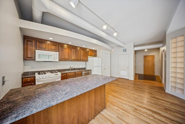 811 S Lytle St Unit 101, Chicago, IL 60607 - kitchen with white appliances, light wood-type flooring, brown cabinetry, a sink, and dark stone countertops