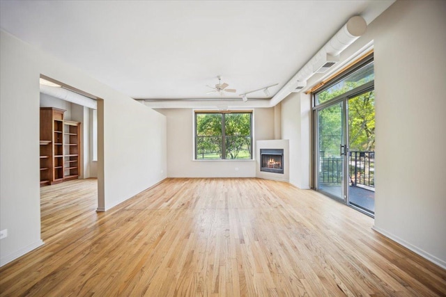 811 S Lytle St Unit 101, Chicago, IL 60607 - unfurnished living room with wood finished floors, a warm lit fireplace, and rail lighting