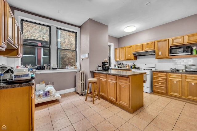 1347 E Hyde Park Blvd, Chicago, IL 60615 - kitchen with white range with gas stovetop, black microwave, under cabinet range hood, decorative backsplash, and light tile patterned flooring