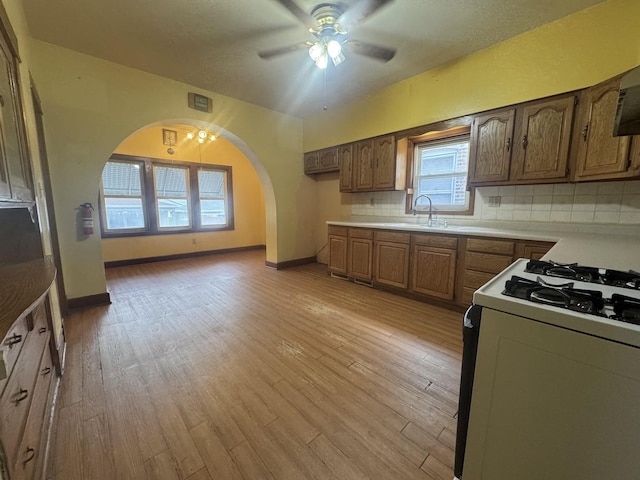 2439 S 57th Ave, Cicero, IL 60804 - kitchen featuring gas range oven, ceiling fan, light wood finished floors, light countertops, and arched walkways