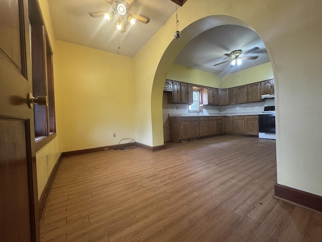2439 S 57th Ave, Cicero, IL 60804 - kitchen featuring a ceiling fan, white range with electric stovetop, arched walkways, dark wood-type flooring, and lofted ceiling