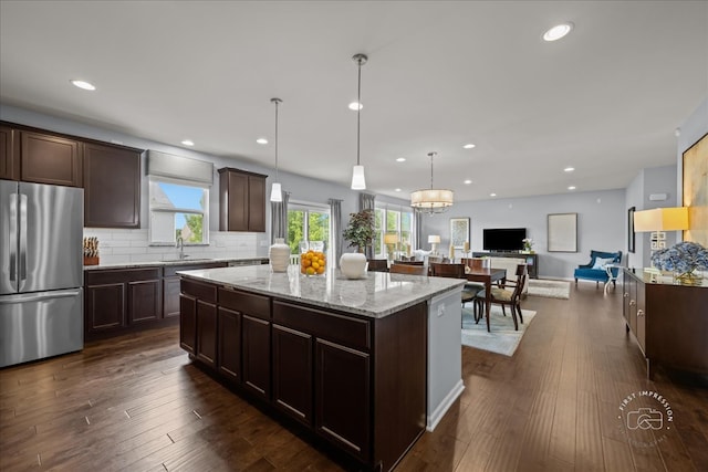 729 Hamilton Dr, South Elgin, IL 60177 - kitchen featuring freestanding refrigerator, dark brown cabinets, a center island, open floor plan, and light stone countertops