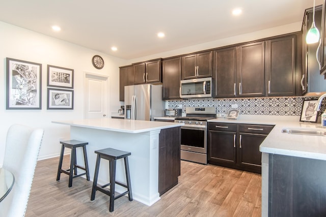 1806 Peyton Ter, Shorewood, IL 60404 - kitchen with appliances with stainless steel finishes, a sink, a breakfast bar, dark brown cabinetry, and light wood finished floors