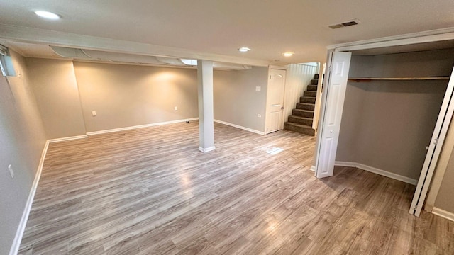 finished basement with recessed lighting, baseboards, light wood-type flooring, and stairs