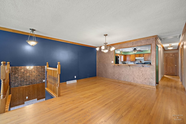 unfurnished room featuring light wood-style flooring, crown molding, a textured ceiling, ceiling fan, and baseboards