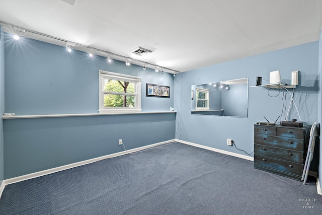 unfurnished bedroom with track lighting, carpet, and baseboards