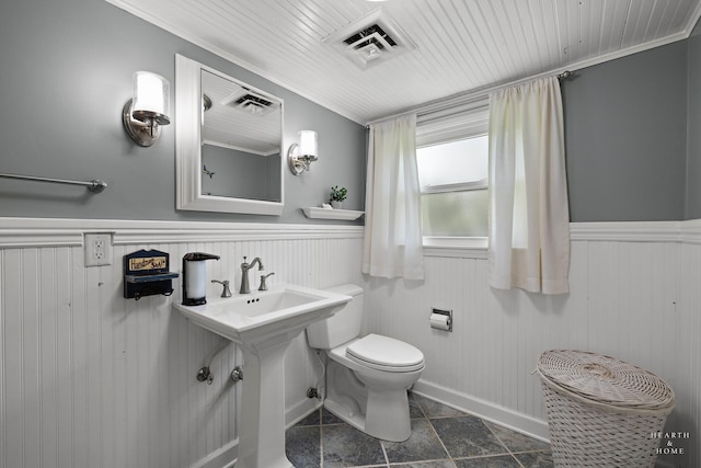 bathroom with toilet, a wainscoted wall, ornamental molding, and stone finish floors