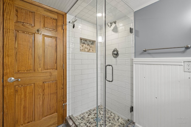 bathroom featuring a shower stall and a wainscoted wall