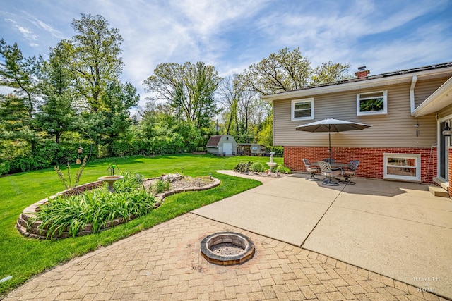 view of patio / terrace featuring a fire pit, an outbuilding, and a storage unit
