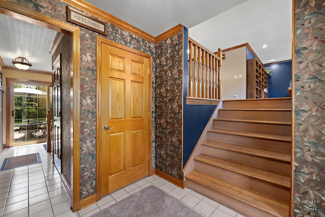 foyer featuring ornamental molding, tile patterned flooring, stairway, wallpapered walls, and baseboards
