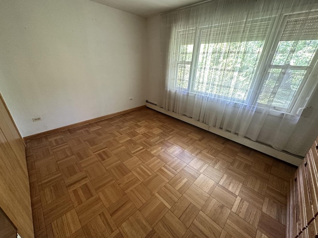 empty room with a baseboard radiator, healthy amount of natural light, and baseboards