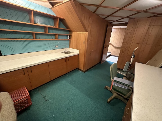 office area featuring wooden walls, a sink, and dark carpet
