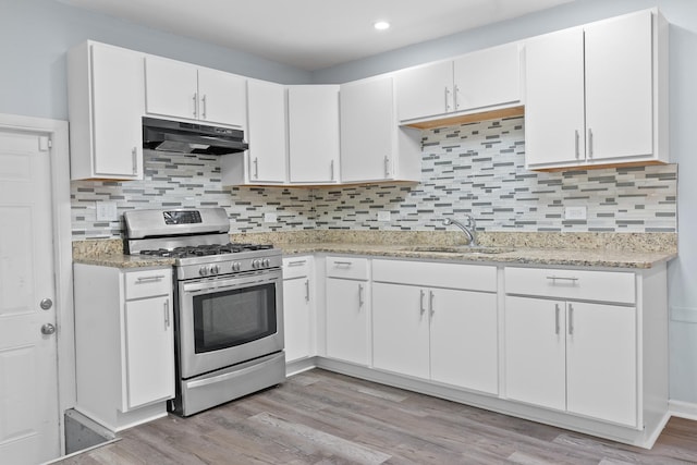 15503 Cherry St, South Holland, IL 60473 - kitchen featuring under cabinet range hood, stainless steel gas stove, a sink, white cabinets, and tasteful backsplash