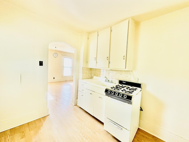 1115 E Wilson St, Streator, IL 61364 - kitchen with white gas range, a sink, light wood-type flooring, arched walkways, and tasteful backsplash