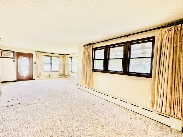 1115 E Wilson St, Streator, IL 61364 - unfurnished living room with a baseboard radiator, carpet, baseboard heating, a textured ceiling, and an AC wall unit