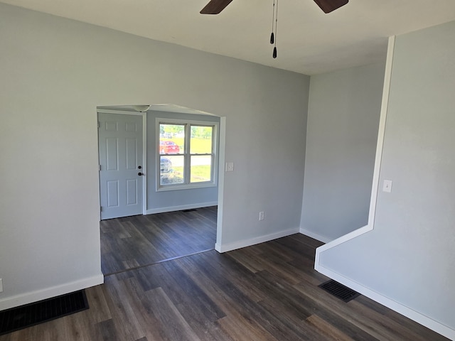 empty room with ceiling fan, baseboards, and dark wood-type flooring