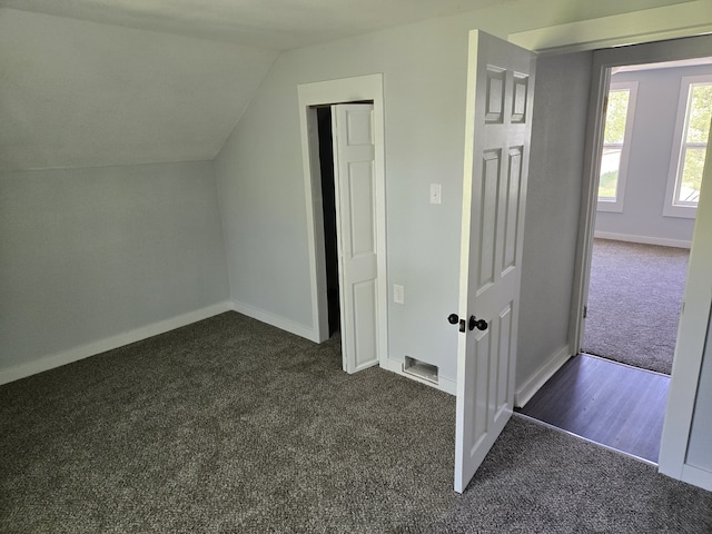 bonus room with dark carpet, lofted ceiling, and baseboards