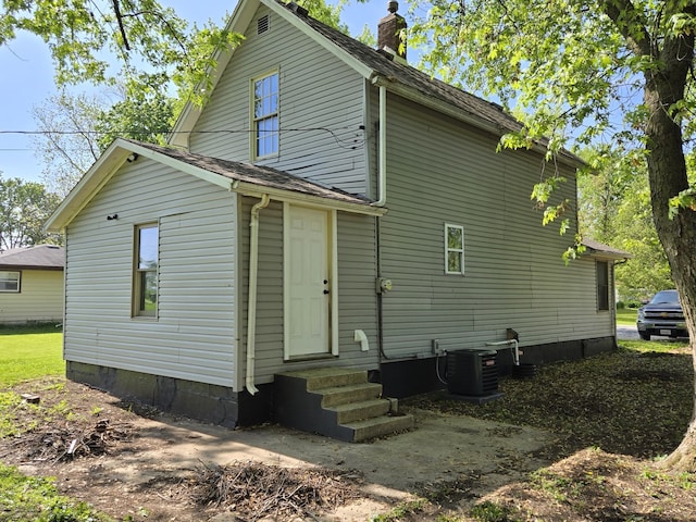 back of property with entry steps, a chimney, and central air condition unit