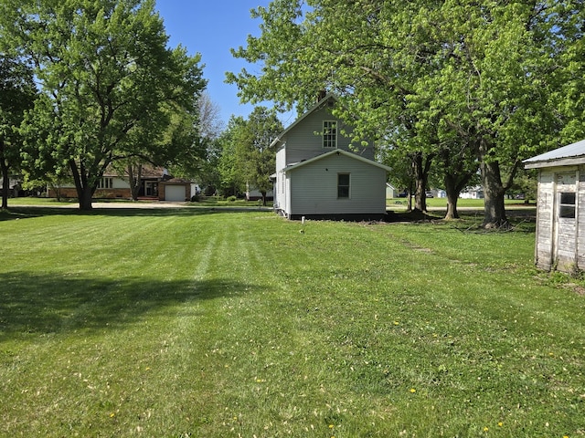 view of grassy yard with a garage and an outbuilding