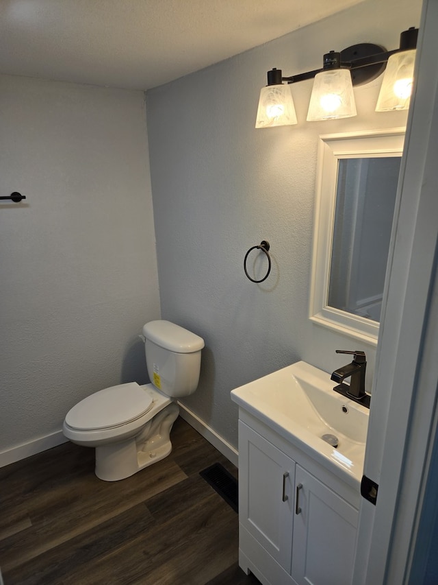 bathroom with baseboards, toilet, wood finished floors, and vanity