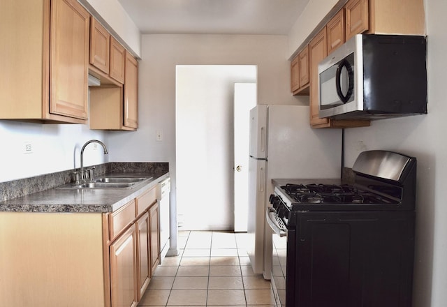 kitchen featuring appliances with stainless steel finishes, a sink, dark countertops, and light tile patterned floors