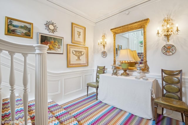 sitting room with a decorative wall, a wainscoted wall, and ornamental molding