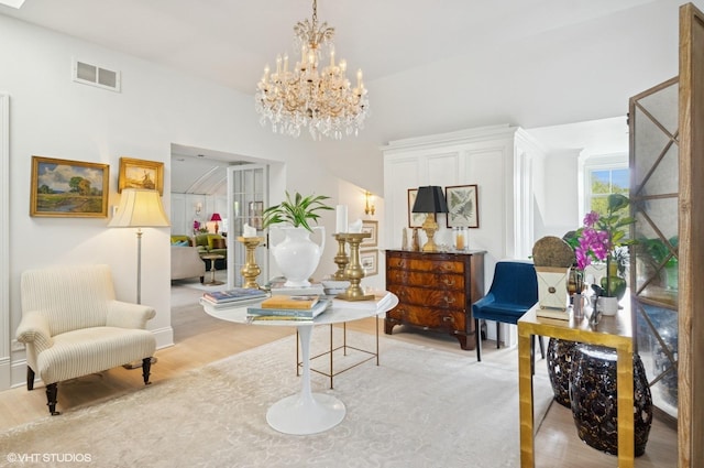 living area with light wood-type flooring, a chandelier, and baseboards