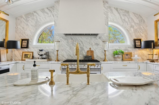 kitchen featuring healthy amount of natural light, decorative backsplash, white cabinetry, and light stone counters