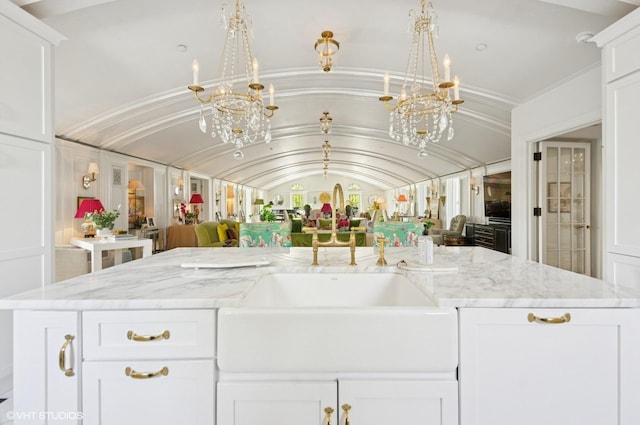 kitchen featuring open floor plan, a chandelier, white cabinets, light stone countertops, and vaulted ceiling