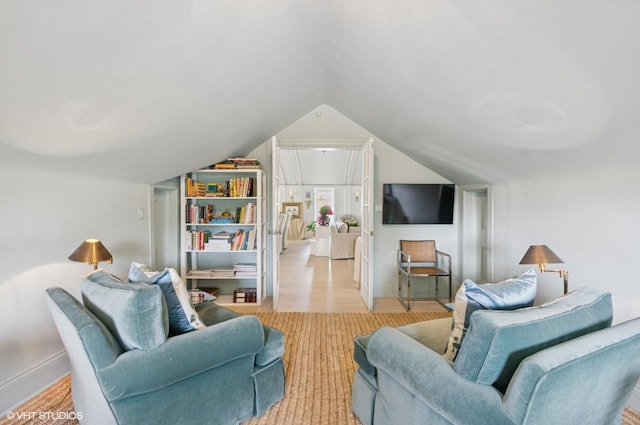 living room featuring lofted ceiling, light wood-type flooring, and baseboards