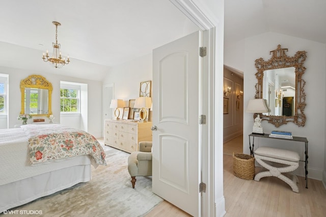 bedroom with lofted ceiling, a chandelier, and wood finished floors