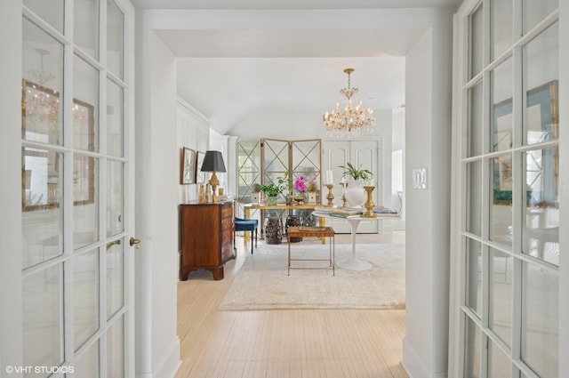 hallway featuring a chandelier, wood finished floors, and vaulted ceiling