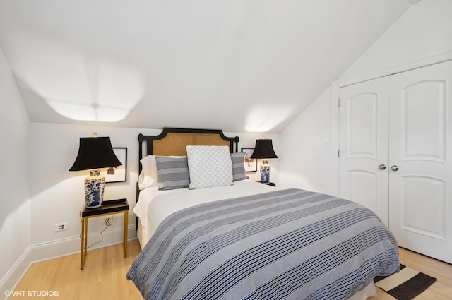 bedroom featuring vaulted ceiling, light wood finished floors, a closet, and baseboards