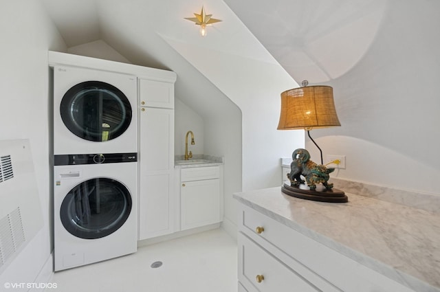 clothes washing area featuring stacked washer / drying machine and cabinet space