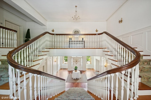 stairs featuring a chandelier, wood finished floors, and ornamental molding